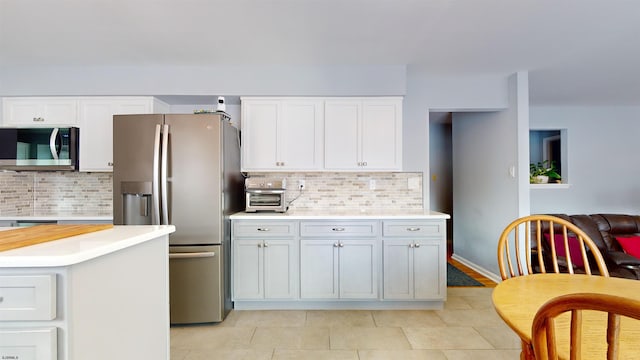 kitchen with white cabinetry, backsplash, appliances with stainless steel finishes, and light tile patterned flooring