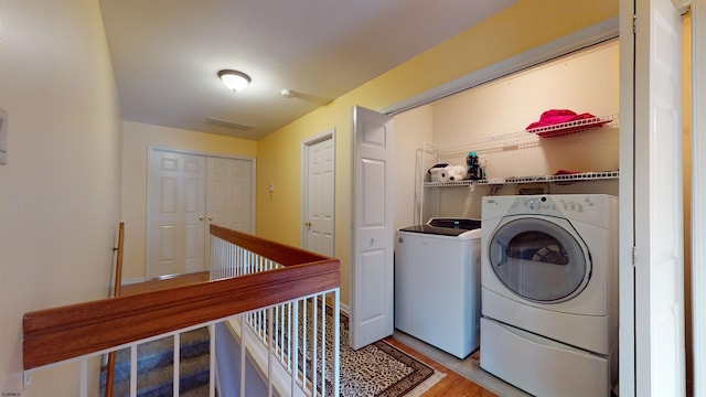 laundry area with wood-type flooring and separate washer and dryer