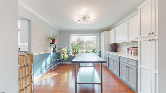 kitchen featuring ornamental molding, white cabinetry, light hardwood / wood-style flooring, and backsplash