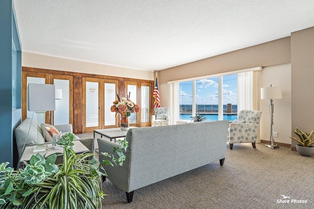 carpeted living room with a water view, french doors, and a textured ceiling