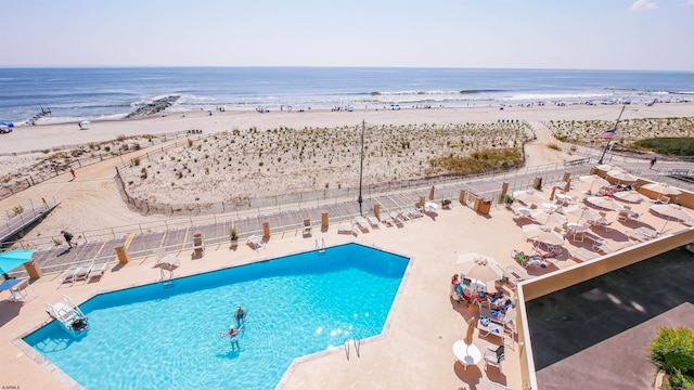 view of swimming pool with a patio area, a view of the beach, and a water view