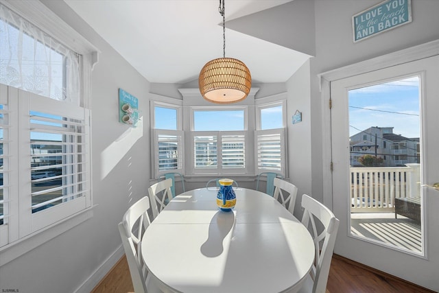 dining space featuring vaulted ceiling and dark hardwood / wood-style floors