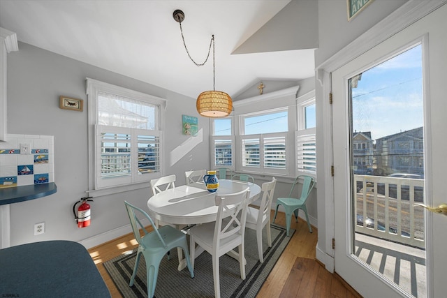 dining area with a wealth of natural light, hardwood / wood-style floors, and vaulted ceiling