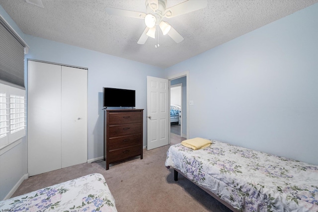 carpeted bedroom featuring a closet, a textured ceiling, and ceiling fan