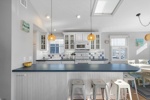 kitchen with white cabinets, decorative light fixtures, plenty of natural light, and white appliances