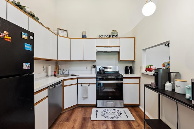 kitchen featuring white cabinets, appliances with stainless steel finishes, hardwood / wood-style flooring, vaulted ceiling, and sink