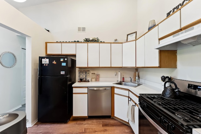 kitchen with light hardwood / wood-style floors, stainless steel appliances, sink, and white cabinets