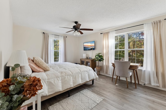 bedroom featuring a textured ceiling, light wood-type flooring, and ceiling fan