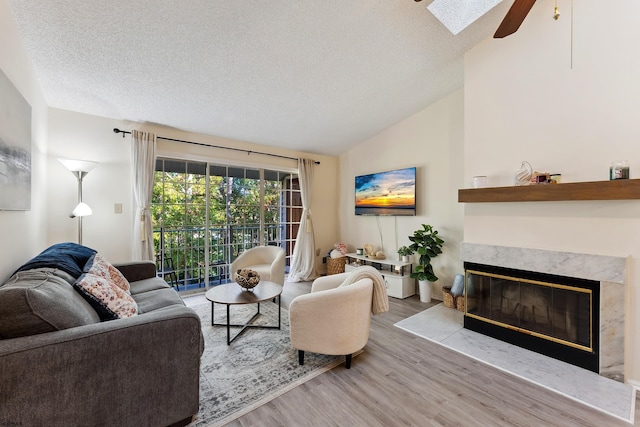 living room featuring ceiling fan, lofted ceiling with skylight, a textured ceiling, and hardwood / wood-style floors