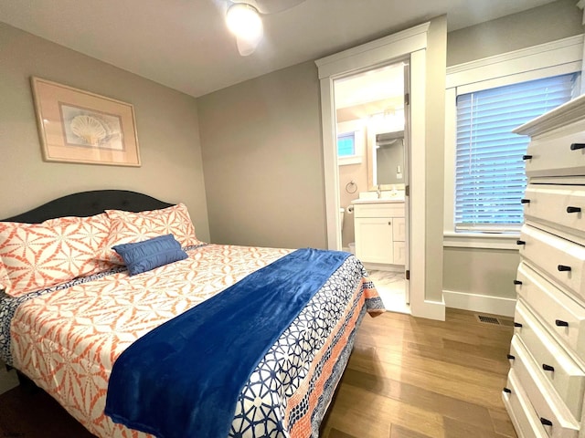 bedroom with hardwood / wood-style floors, ensuite bath, sink, and ceiling fan