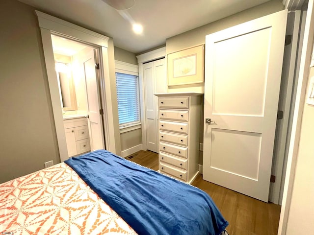 bedroom featuring ensuite bath, a closet, and dark hardwood / wood-style flooring