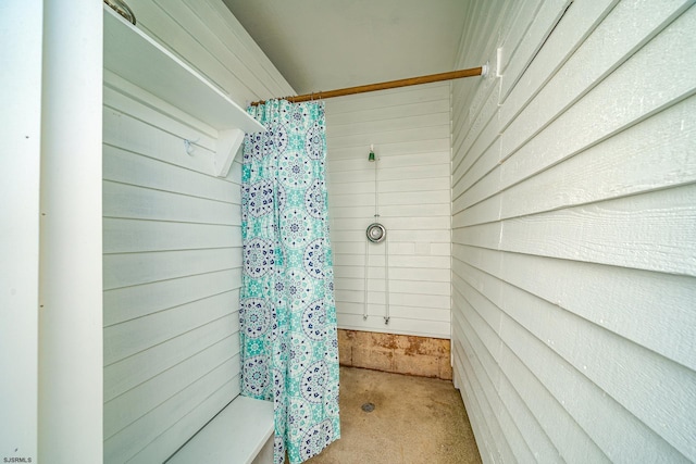 bathroom featuring walk in shower and wood walls