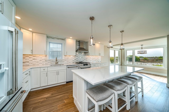 kitchen featuring wall chimney range hood, white cabinets, and high end appliances