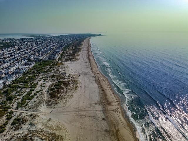 aerial view at dusk featuring a water view and a view of the beach