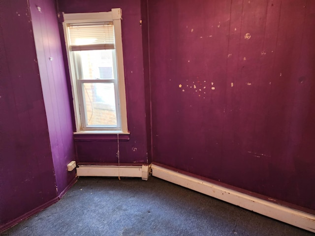 unfurnished room featuring carpet and a baseboard heating unit