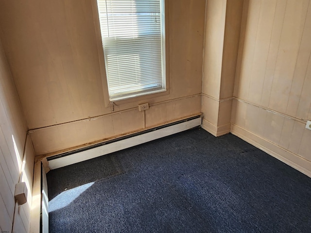 unfurnished room with wood walls and dark colored carpet