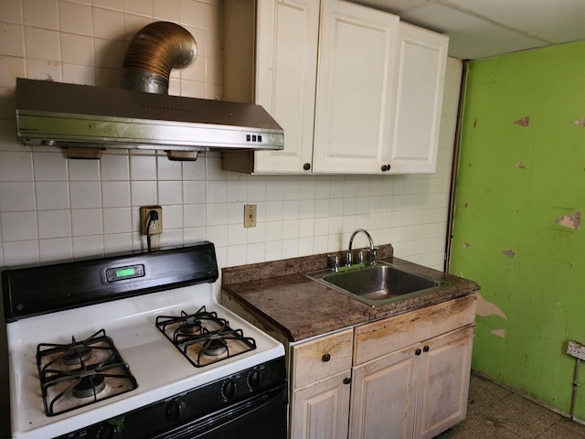 kitchen featuring exhaust hood, a wood stove, sink, white range with gas cooktop, and white cabinets