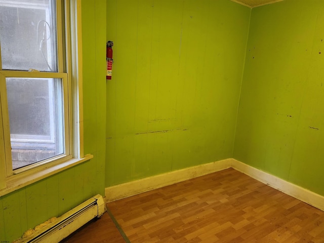 spare room featuring wood-type flooring and a baseboard radiator