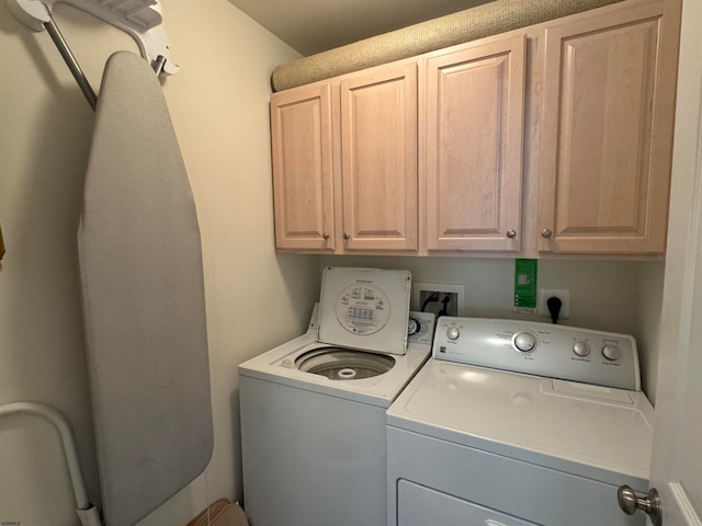 laundry room featuring separate washer and dryer and cabinets