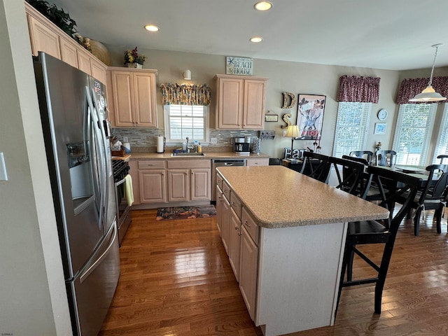 kitchen featuring a breakfast bar, decorative light fixtures, stainless steel appliances, and dark hardwood / wood-style floors