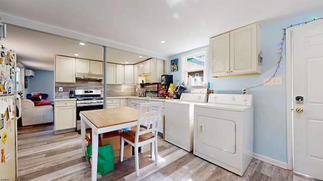 kitchen with washing machine and dryer, light wood-type flooring, stainless steel range with gas stovetop, white cabinets, and decorative backsplash