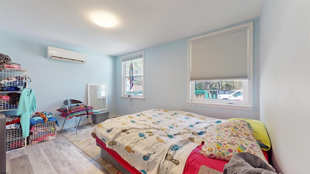 bedroom featuring light hardwood / wood-style flooring, an AC wall unit, and multiple windows