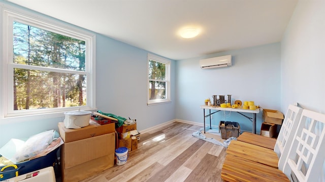 game room with light hardwood / wood-style floors, a wall unit AC, and a healthy amount of sunlight