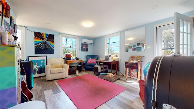 office area with light hardwood / wood-style floors, an AC wall unit, and a wealth of natural light