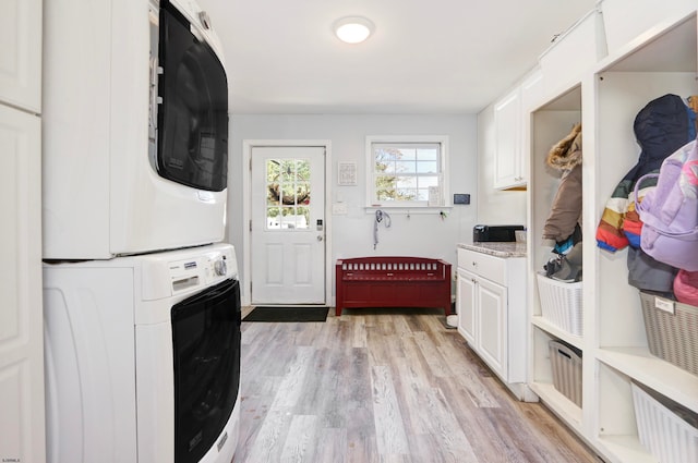 laundry room featuring cabinets, stacked washer and dryer, and light wood-type flooring