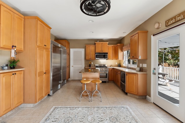 kitchen featuring light tile patterned floors, a kitchen breakfast bar, sink, a center island, and premium appliances