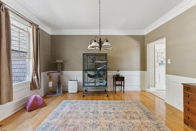 living area with hardwood / wood-style floors, crown molding, and a chandelier