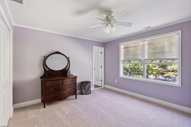 carpeted bedroom featuring crown molding, a closet, and ceiling fan