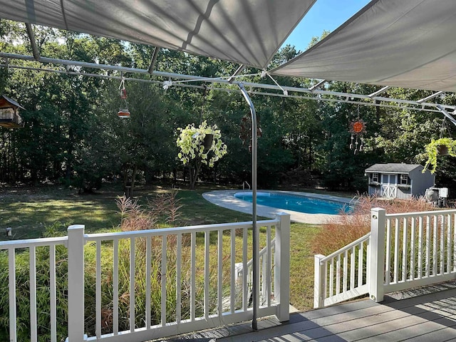 view of swimming pool featuring a storage shed, a deck, and a lawn