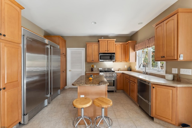 kitchen featuring light tile patterned floors, a kitchen breakfast bar, sink, a center island, and premium appliances