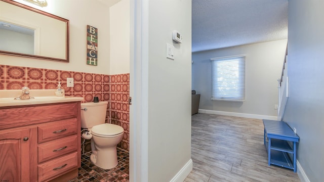 bathroom with hardwood / wood-style floors, a textured ceiling, tile walls, toilet, and vanity