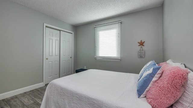 bedroom with a closet, a textured ceiling, and wood-type flooring