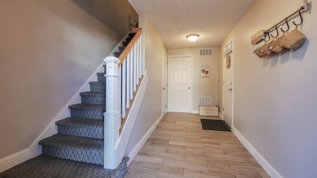 doorway featuring light hardwood / wood-style flooring and a textured ceiling