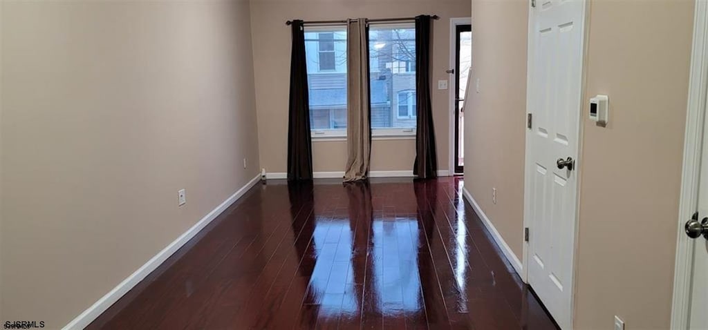 unfurnished room with dark wood-type flooring