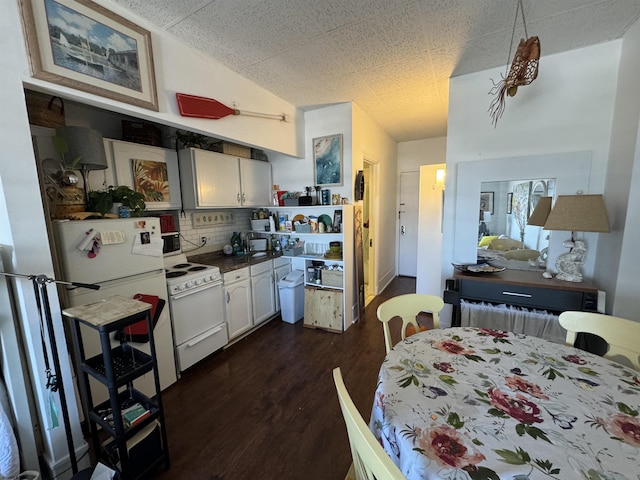 kitchen with white cabinetry, dark hardwood / wood-style floors, backsplash, vaulted ceiling, and white appliances