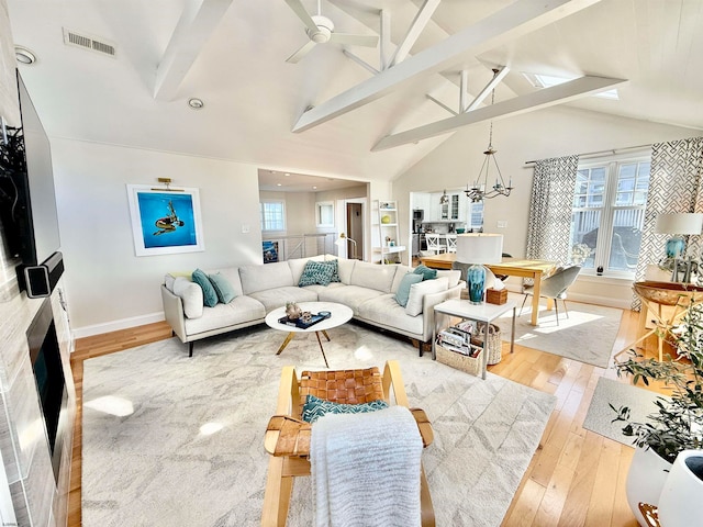 living room featuring beam ceiling, light hardwood / wood-style flooring, high vaulted ceiling, and ceiling fan with notable chandelier