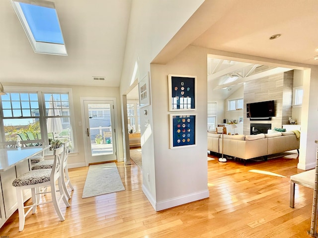 entryway with hardwood / wood-style floors, vaulted ceiling with skylight, and a fireplace