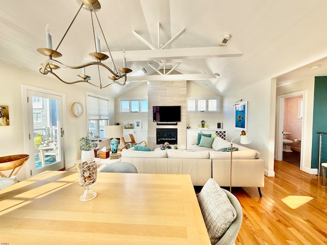 dining area featuring lofted ceiling with beams, a wealth of natural light, a fireplace, and hardwood / wood-style floors