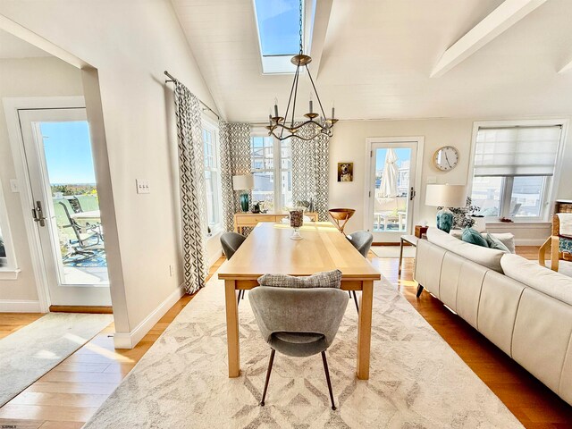 dining space with hardwood / wood-style flooring, vaulted ceiling with skylight, and a wealth of natural light