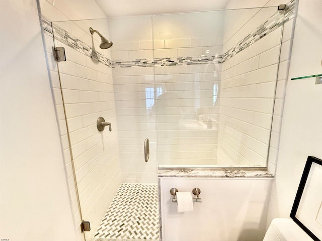 bathroom featuring a shower with door and toilet