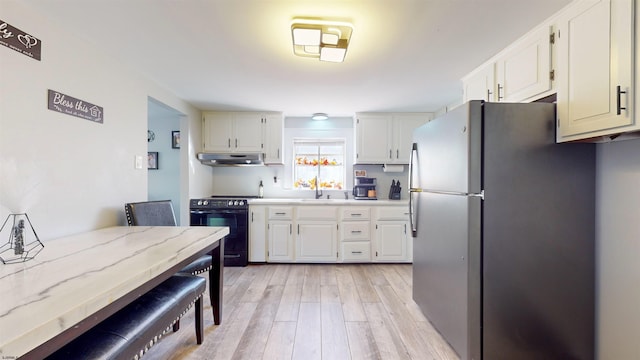 kitchen with light stone countertops, black electric range oven, white cabinetry, stainless steel refrigerator, and light hardwood / wood-style flooring