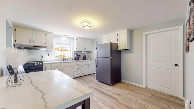 kitchen featuring stainless steel fridge, electric range, white cabinetry, and light wood-type flooring