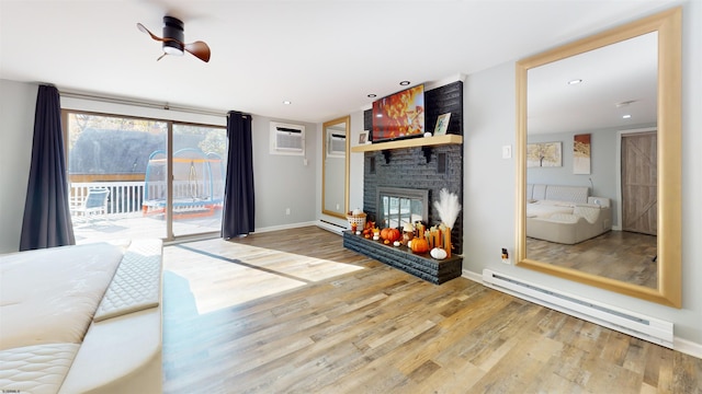 unfurnished living room featuring a baseboard heating unit, hardwood / wood-style flooring, an AC wall unit, and a fireplace