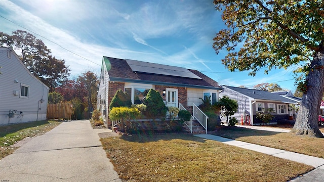 bungalow with a front lawn and solar panels