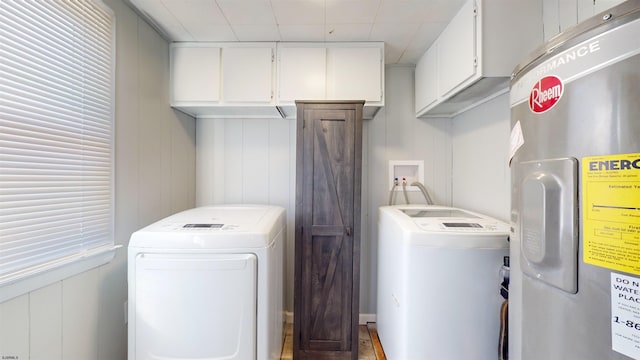 washroom with cabinets, wood walls, electric water heater, and washing machine and dryer