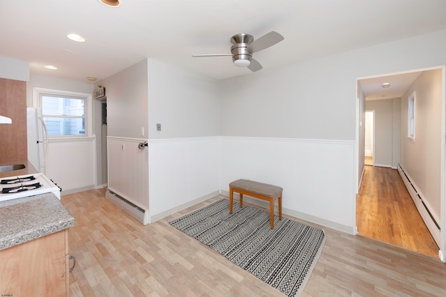 kitchen featuring white appliances, light hardwood / wood-style floors, a baseboard heating unit, and ceiling fan